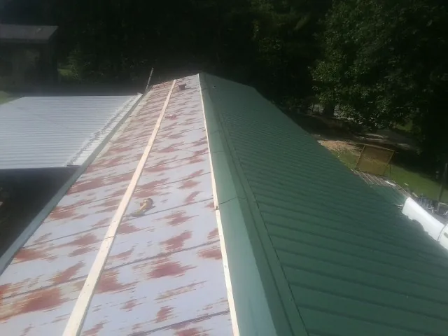 Old rusted panels beside newly installed green metal roofing — Wind Damage Roof Repair by Roofing Brothers in Signal Hill