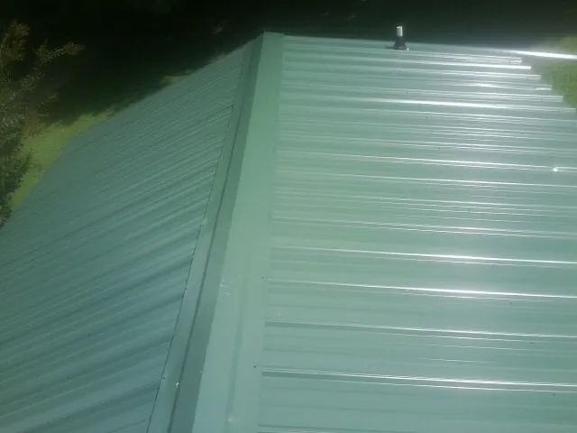 New green metal panels meeting at the ridge of a roof — Flat Roof Repair work by our crew in Signal Hill