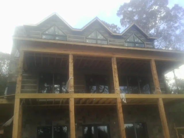 Dormers and porch framing on a large log home under construction — Roof Coating work by our crew in Signal Hill