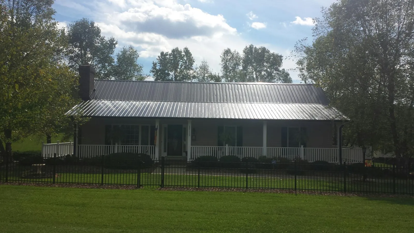 Gray metal roof on a brick ranch with a full width front porch — Gutter Guard Installation work by our crew in Signal Hill