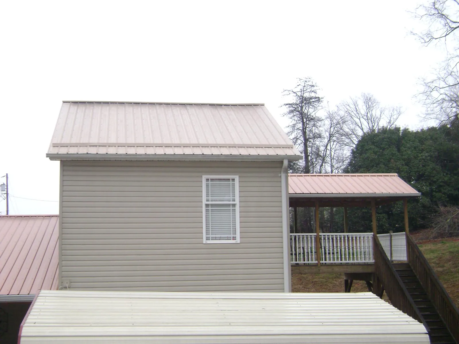 Tan metal roofs on a two story addition and attached porch, from a Roof Replacement job in Signal Hill