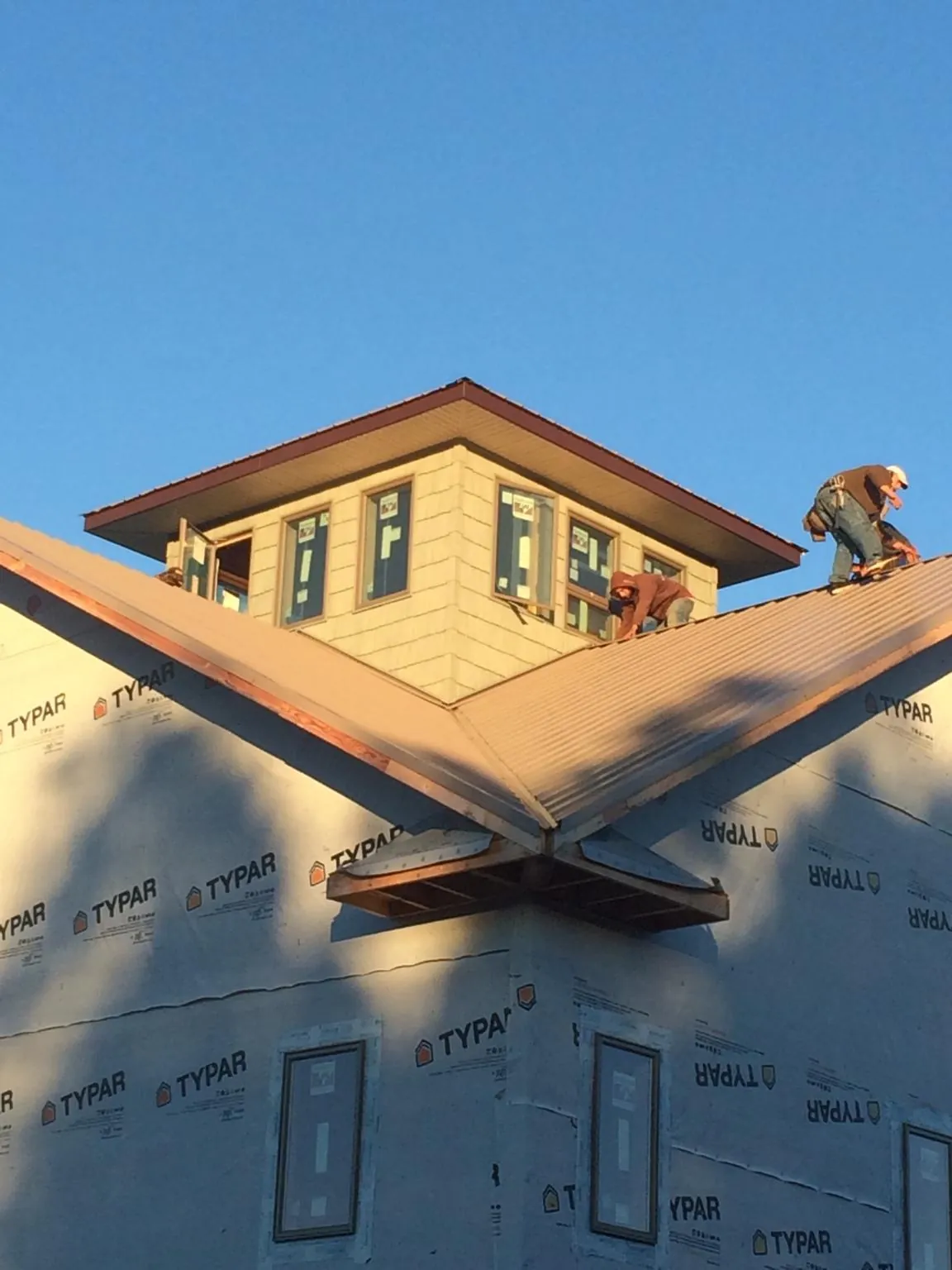 Roofers working around a rooftop cupola on a new metal roof at sunset — Roof Waterproofing in Signal Hill by Roofing Brothers